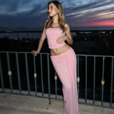 Woman in a pink outfit standing on a balcony at dusk.